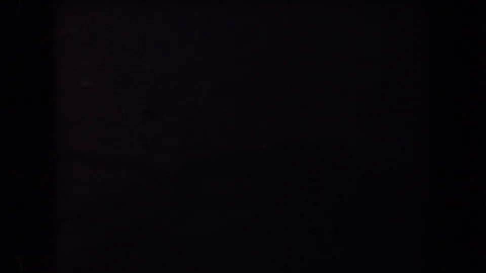 Late frame from the 1958 Arizona desert drive, showing faint hills and sky while the foreground is nearly black.