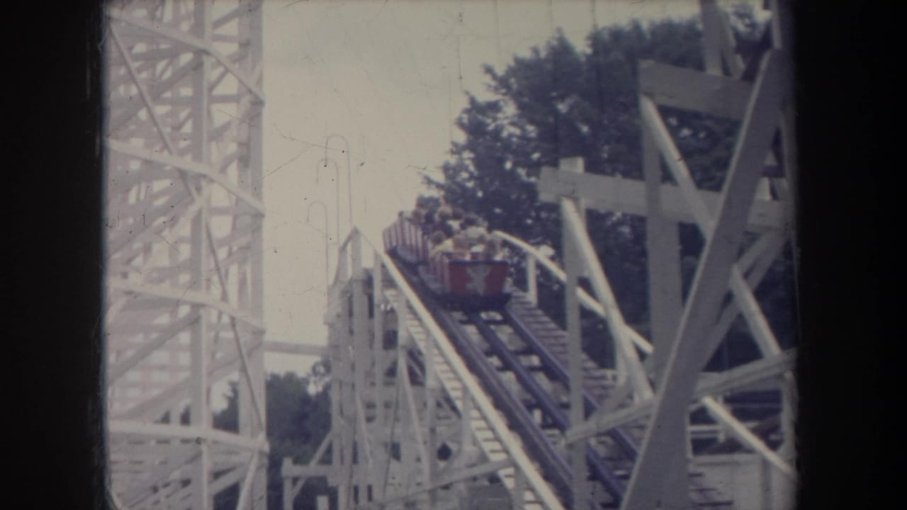 1968 Michigan 8mm frame showing a red roller coaster car with riders ascending a white wooden lift hill.