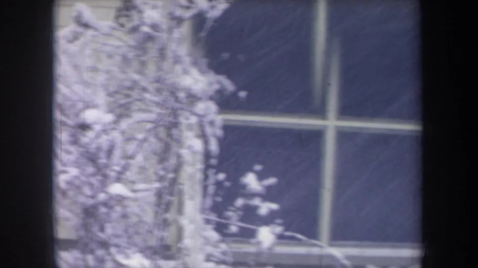 1968 Michigan 8mm frame showing a snow-covered window and nearby branches during a winter storm.