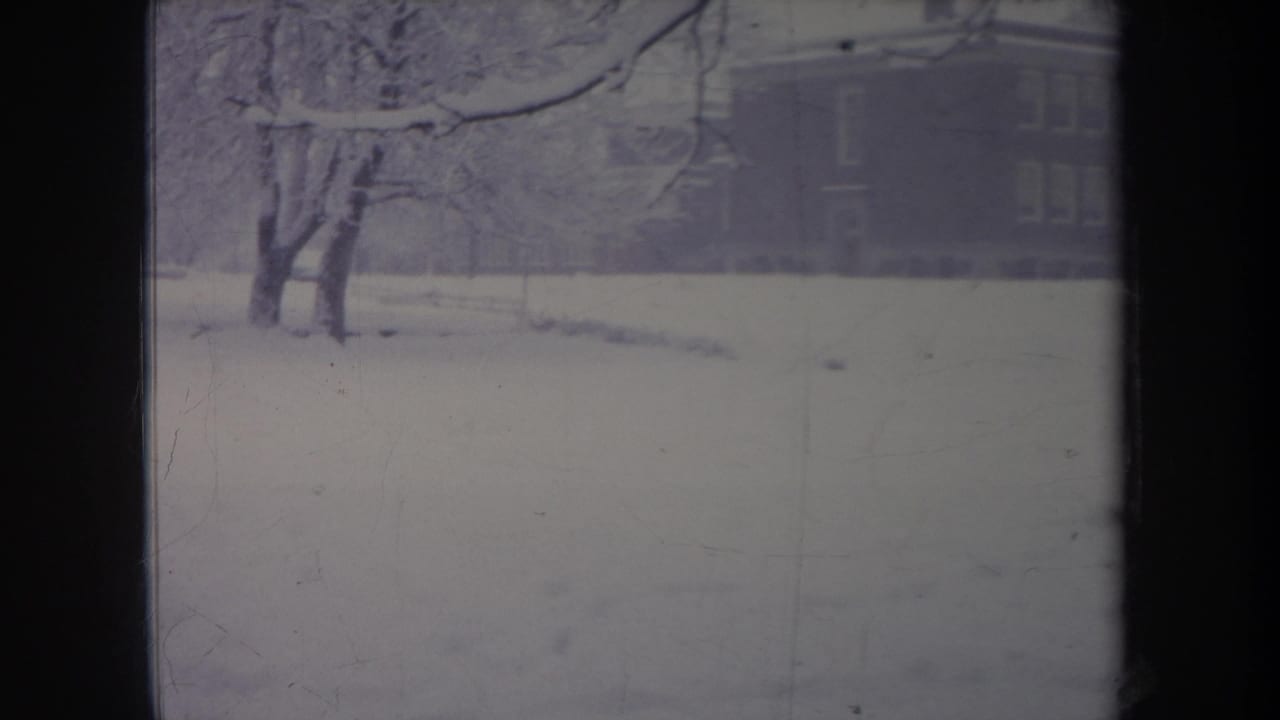 1968 Michigan 8mm frame showing snowy trees and a large house partly visible behind the winter haze.