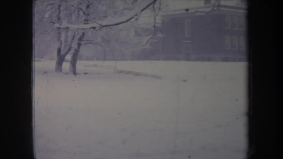 1968 Michigan 8mm frame showing snowy trees and a large house partly visible behind the winter haze.