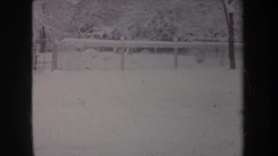 1968 Michigan 8mm frame showing a snow-covered yard, fence line, and winter trees in soft faded color.