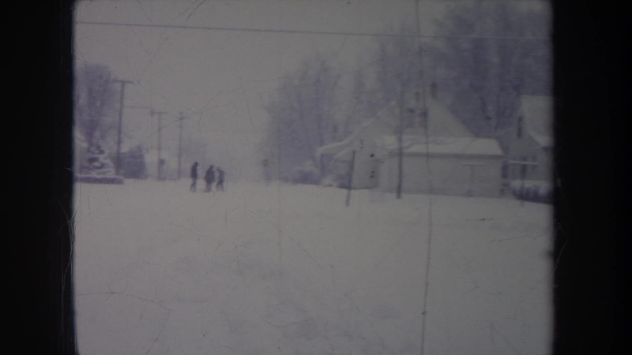 1968 metadata-supported 8mm winter street view in Michigan, showing distant people against a snowy suburban backdrop.
