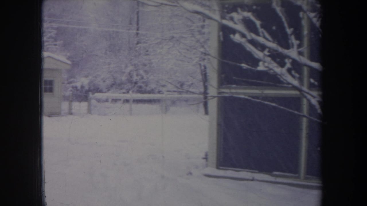 1968 Michigan 8mm frame showing a snowy yard, bare trees, a small shed, and part of a light-colored house.