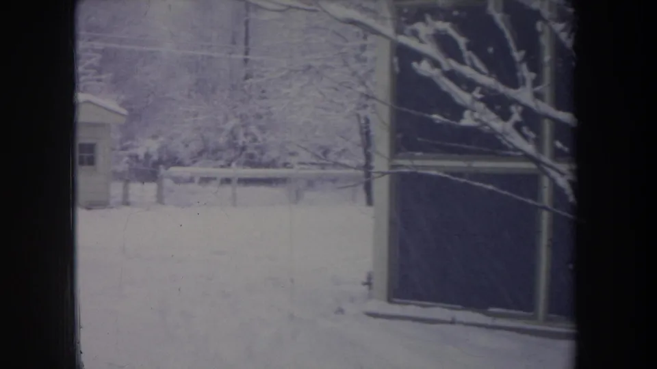 1968 Michigan 8mm frame showing a snowy yard, bare trees, a small shed, and part of a light-colored house.