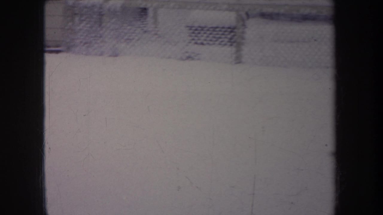 1968 Michigan 8mm frame with a snow-covered fenced setting, muted color, and visible film wear across the scan.