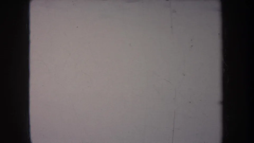 A washed, scratched 8mm frame from the Michigan home movie with dark vertical borders and indistinct snowy yard detail.