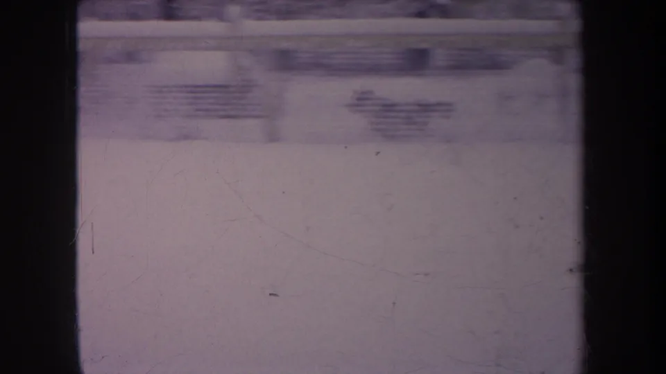 1968 Michigan 8mm frame with a blurred snowy backyard, dark framing, and low yard objects beyond the snow.