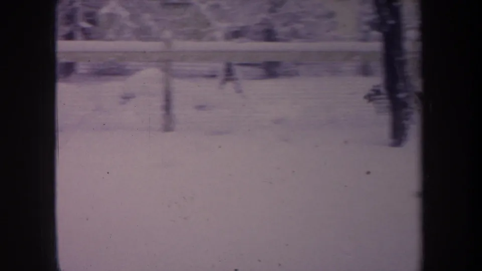 1968 Michigan 8mm frame with a brown dog running through a snowy fenced backyard.