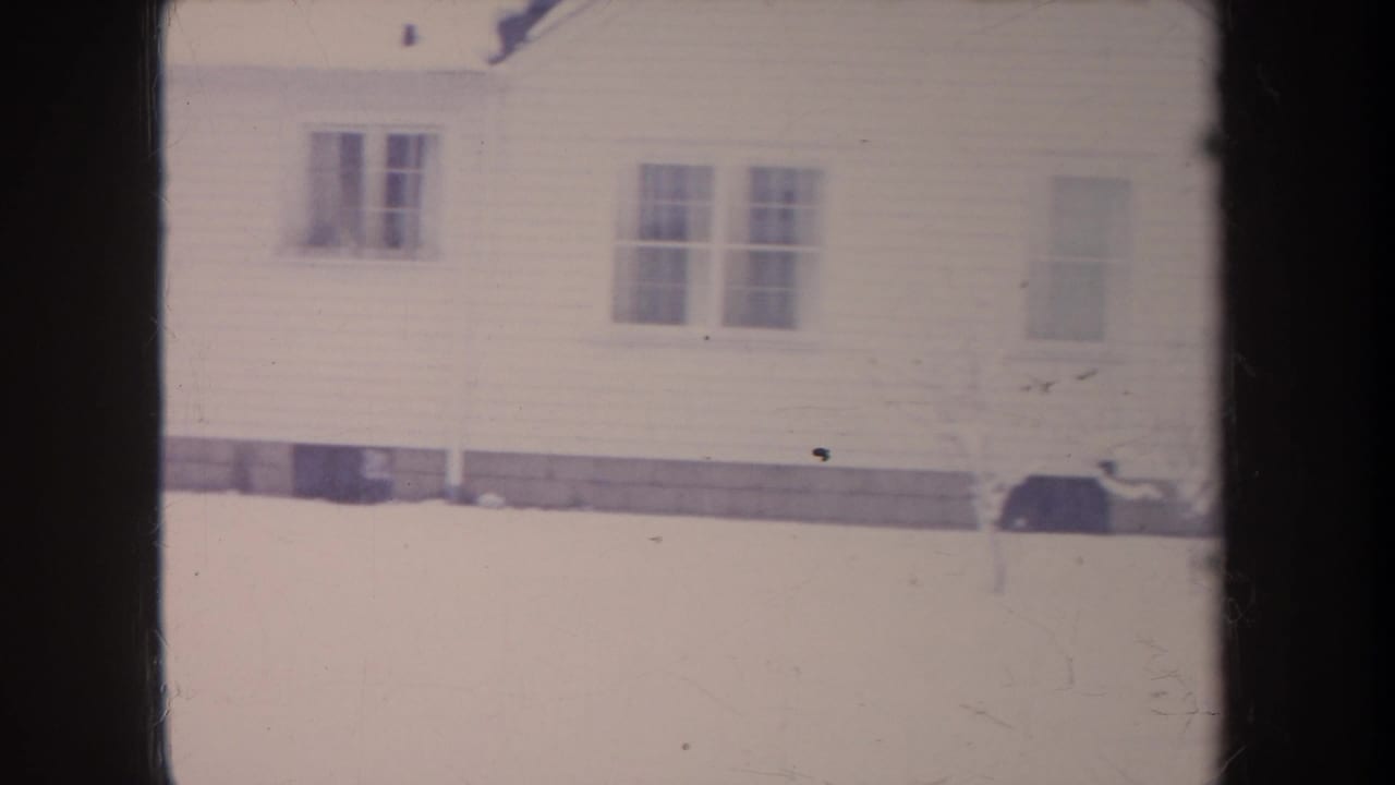 White house wall with windows above a snowy yard.