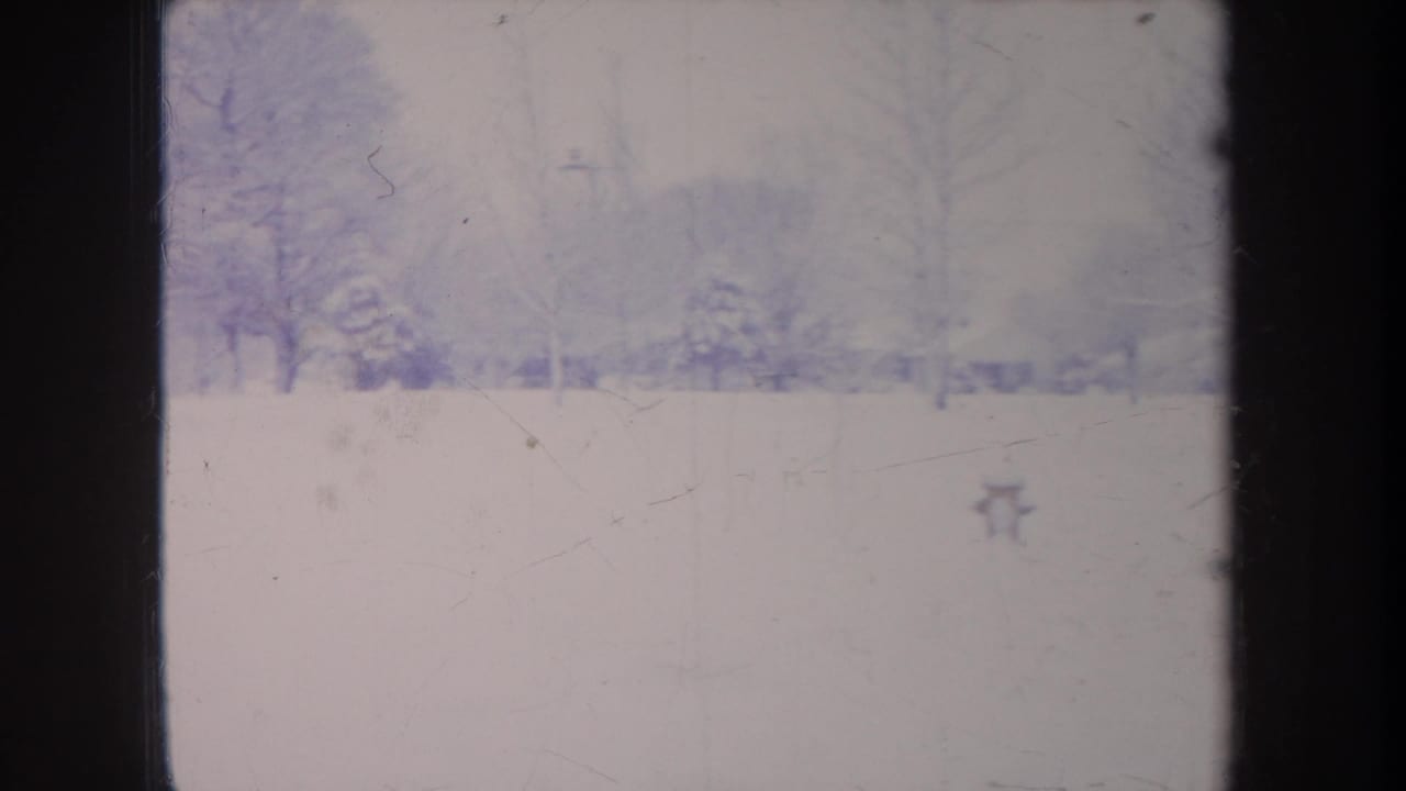 Soft 8mm view of a Michigan snowy landscape in 1968, with bare trees, a hazy background, and visible film-frame border.