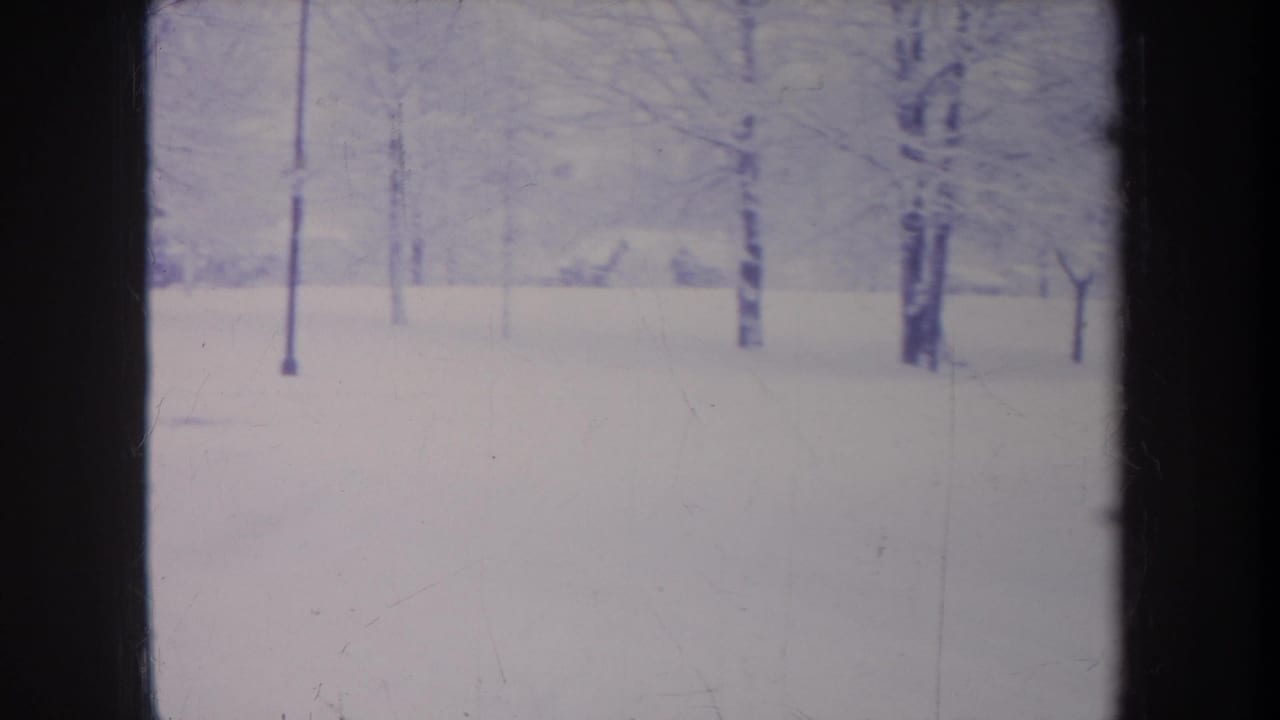 1968 Michigan 8mm frame showing a snow-covered open area with scattered bare trees and soft blue-gray winter tones.