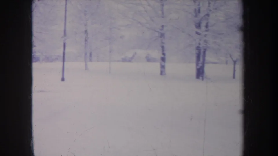 1968 Michigan 8mm frame showing a snow-covered open area with scattered bare trees and soft blue-gray winter tones.