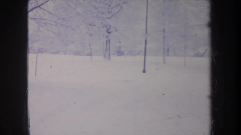 1968 Michigan winter home-movie frame with bare trees over a snowfield, faded color, and visible 8mm film borders.