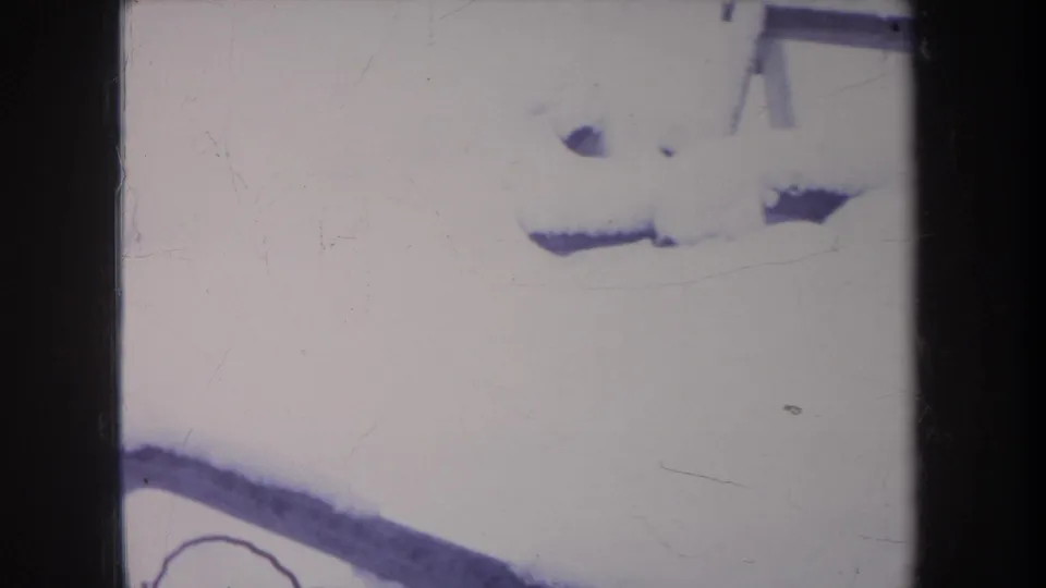 1968 Michigan 8mm frame showing deep backyard snow, a partial bench edge, and the dog partly obscured near the bottom of the frame.