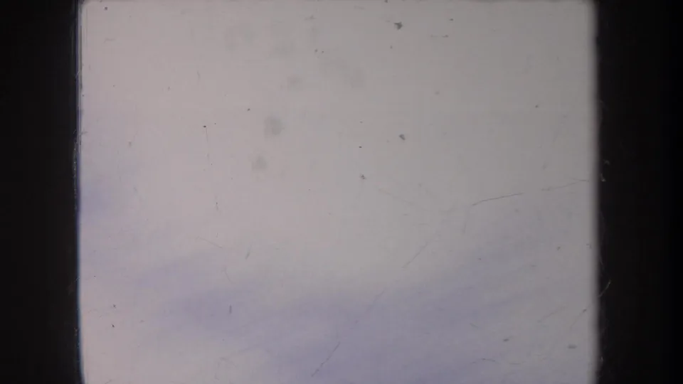 Pale 8mm frame from the Michigan winter clip showing mostly snow or bright exterior surface with scratches, dust, and dark gate edges.