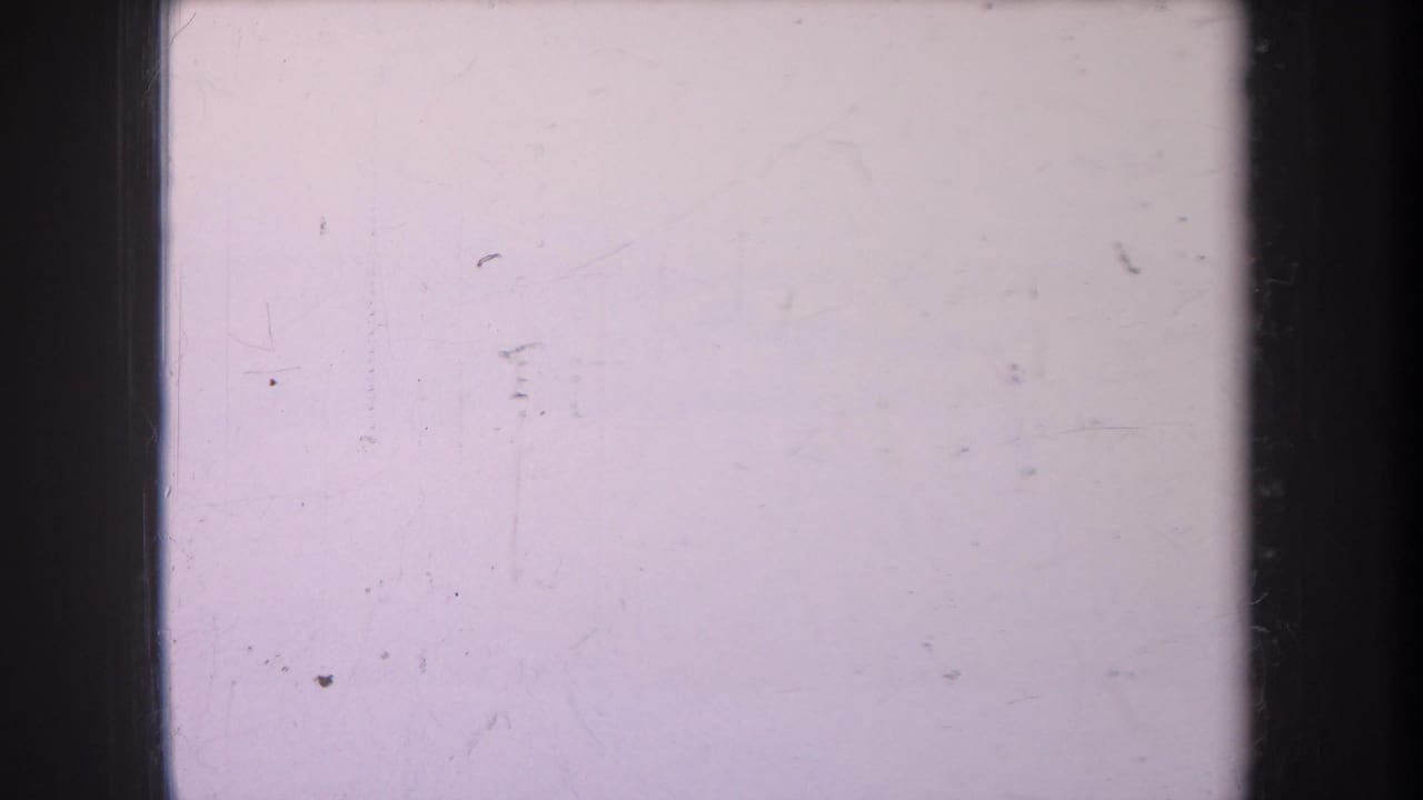 Mostly blank pale film frame with black borders and small dust marks.