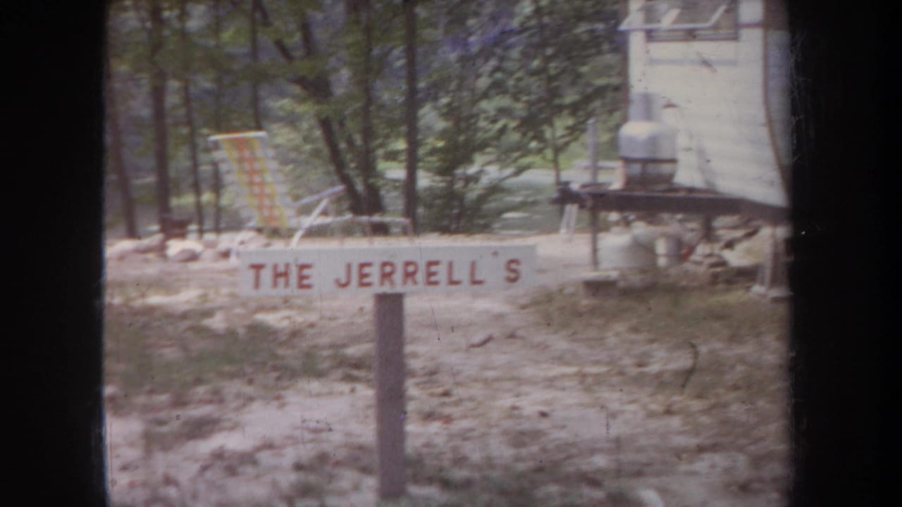A 1968 Michigan campsite view shows the Jerrell family sign, a folding chair, trees, and part of a light-colored structure.