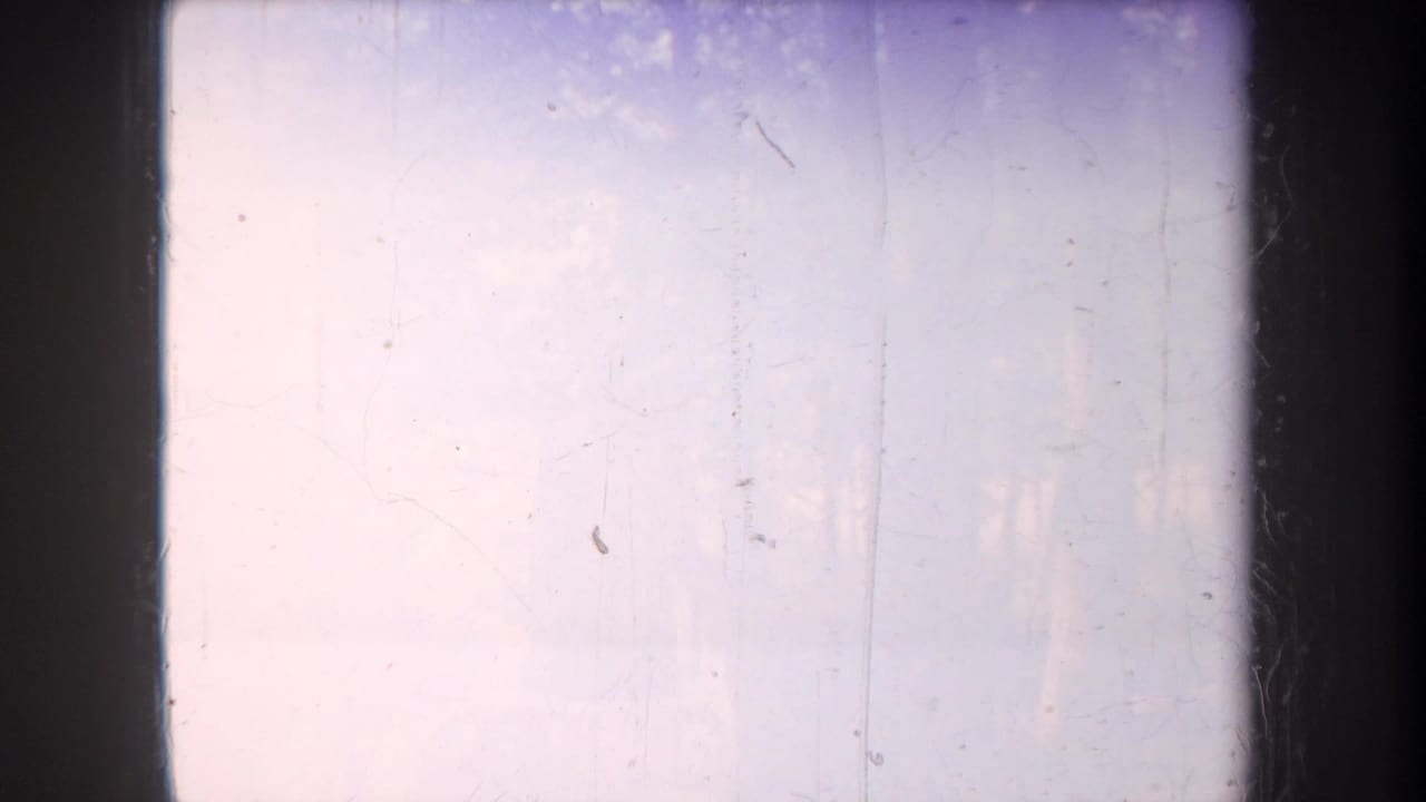 The final 8mm frame is mostly pale and overexposed, with faint scratches and minimal readable campsite detail.