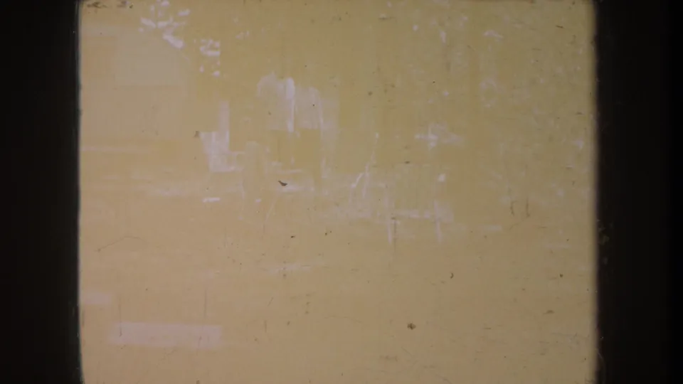 Faded 1968 Michigan 8mm frame with barely visible figures, chairs, trees, dust, scratches, and dark film borders.