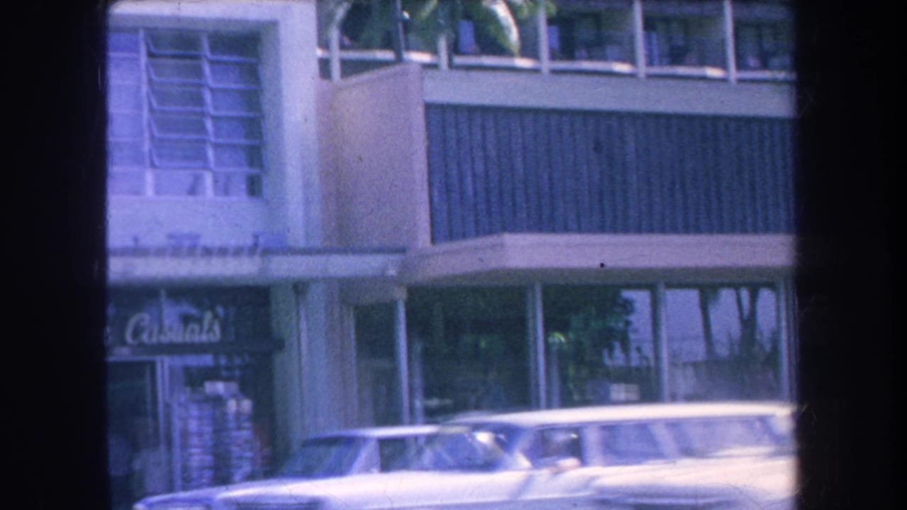 Storefronts and parked car below a modern building facade, with Lurline Casuals sign visible.