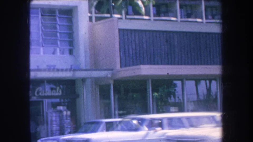 1969 Hawaii commercial street frame showing a parked car, upper windows, and a visible Lurline Casuals storefront sign.