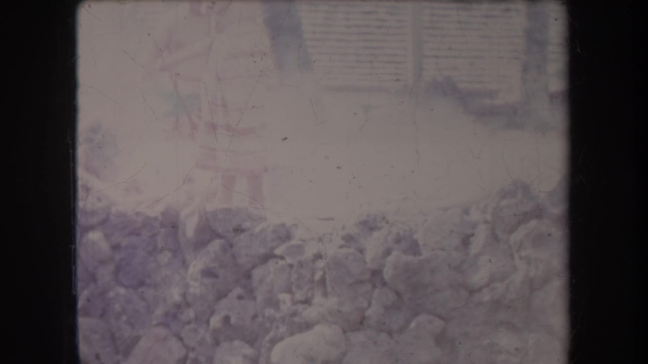 1969 Hawaii 8mm frame showing a low stone wall or rocks with pale steam or haze rising in a faded outdoor scene.
