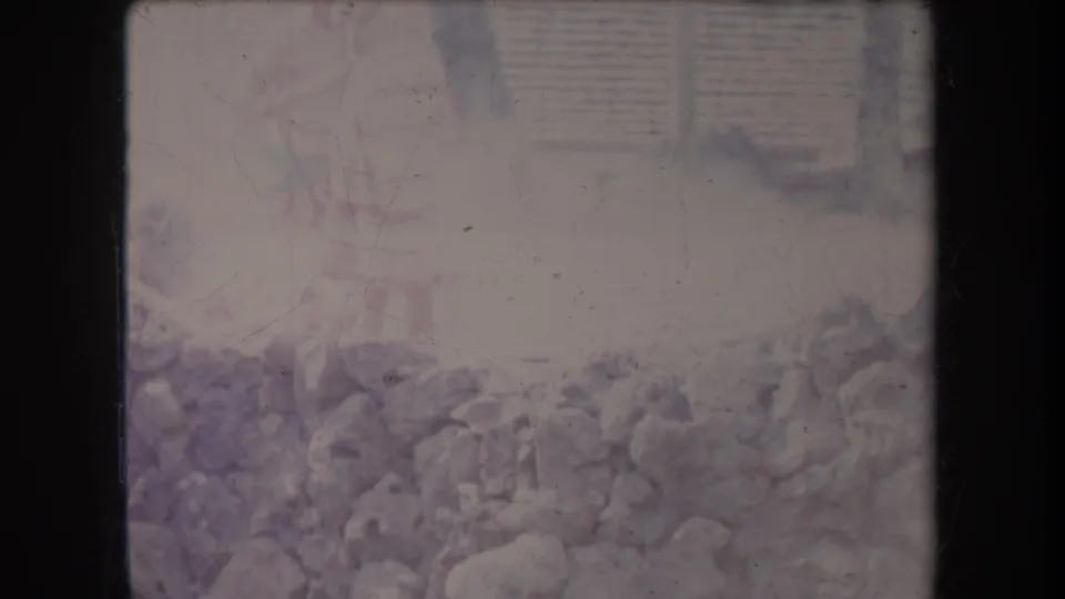 1969 Hawaii 8mm frame showing a low stone wall or rocks with pale steam or haze rising in a faded outdoor scene.