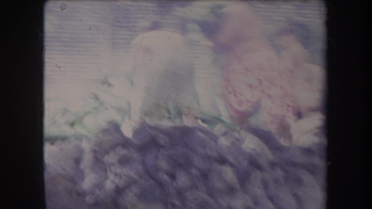 Overexposed view of people and fabric near a smoky outdoor pit.