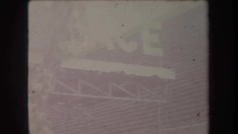 Faded 8mm frame from Hawaii showing a bright roofline, railing, foliage, and tropical building forms.