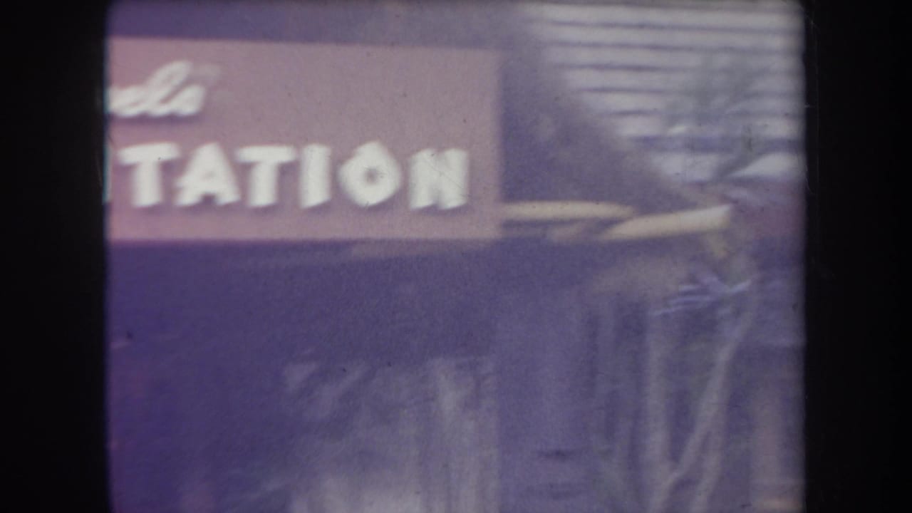1969 Hawaii 8mm frame showing a partially legible plantation sign at a tropical themed attraction.