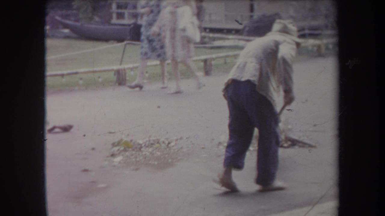 The 1969 Hawaii scene shows the sweeper bending over the pavement while a woman passes in the background near a railing.