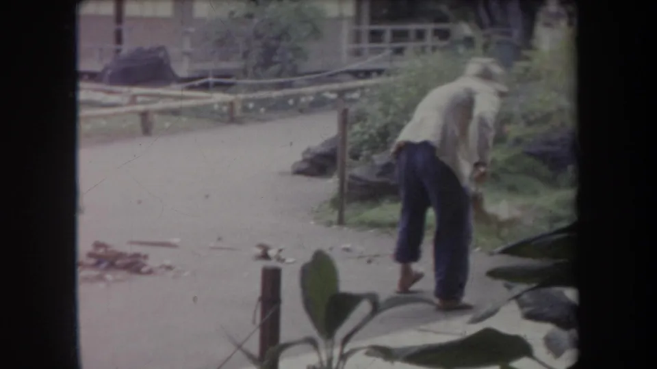 The final 1969 Hawaii frame shows the man from behind, sweeping near tropical plants, a post, and a low wooden railing.