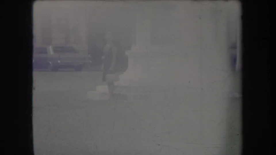 Faded Hawaii home-movie frame with a faint parked car, pavement, and a partially visible person near the top edge.