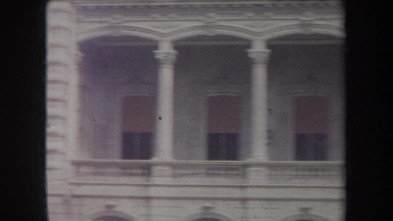 1969 Hawaii 8mm view of a classical building facade with columns, balconies and shuttered windows.