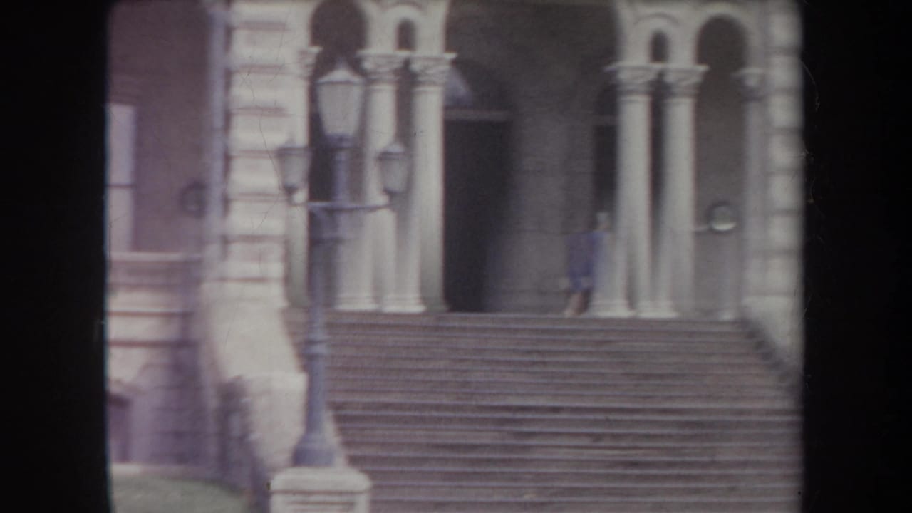 1969 Hawaii exterior showing steps, arched doorways, street lamps and a woman in blue near the entrance.