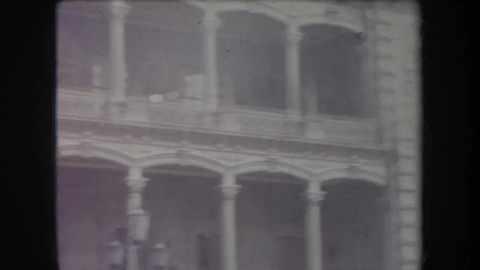 1969 Hawaii home-movie frame showing a soft, grainy view of arched windows and columns on a stone building exterior.