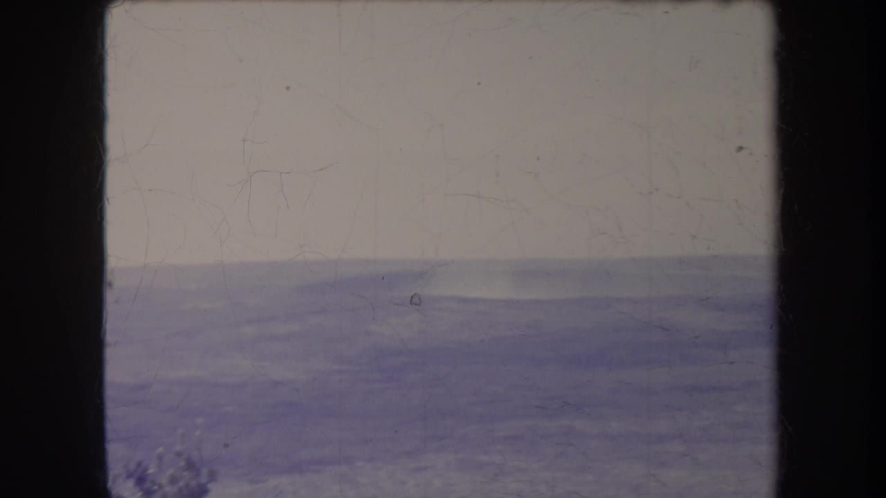Hazy distant landscape with a pale sky and blue-toned ridge bands.
