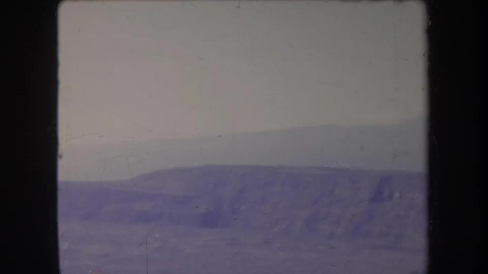 1969 Hawaii 8mm view of broad rocky terrain and distant hills, softened by haze and faded film color.