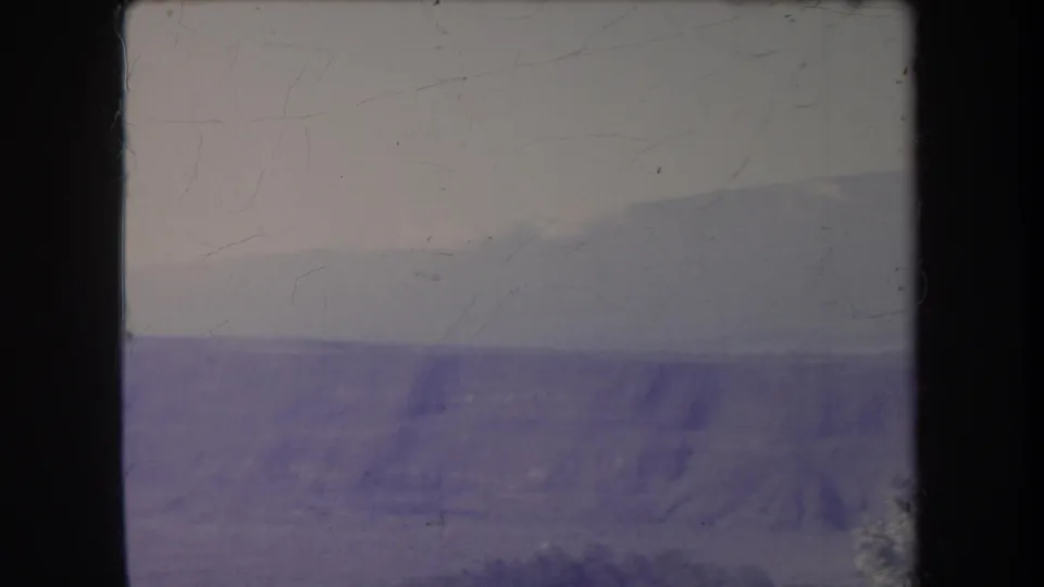 1969 Hawaii landscape frame showing hazy rocky hills and a faint horizon, with 8mm grain and color fading.