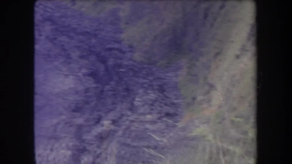 1969 Hawaii 8mm frame looking along a rocky ravine floor bordered by uneven dirt slopes and brush.
