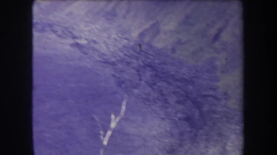 Faded 1969 Hawaii 8mm frame showing a hazy mountain surface or ridge area with scratches, grain, and blue-purple color shift.