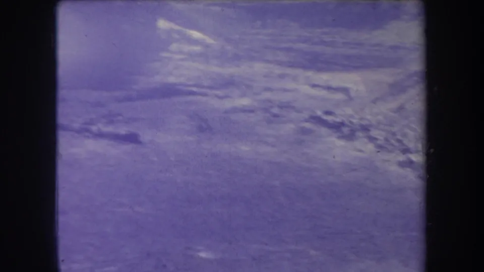 Faded 1969 Hawaii 8mm view of a distant ridge line softened by haze, with visible grain, scratches, and purple-blue color aging.