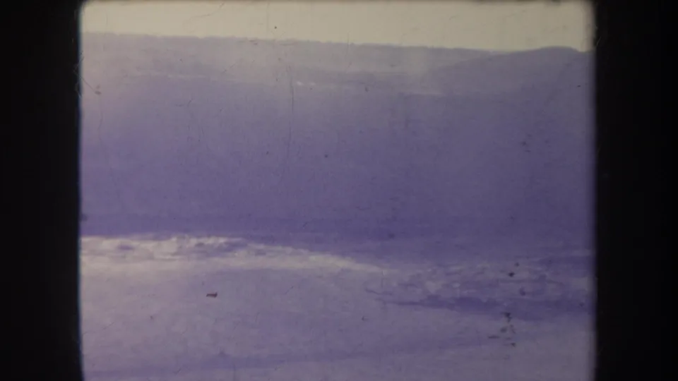 1969 Hawaii 8mm landscape frame with a distant ridge, bright heat haze, soft horizon, and visible aged-film grain.