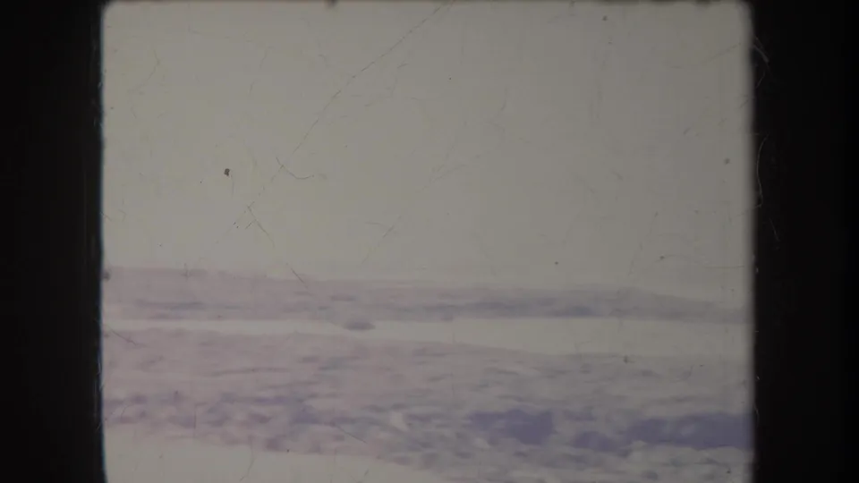1969 Hawaii 8mm frame showing a pale beach and waterline with soft focus, scratches, and dark film gate borders.