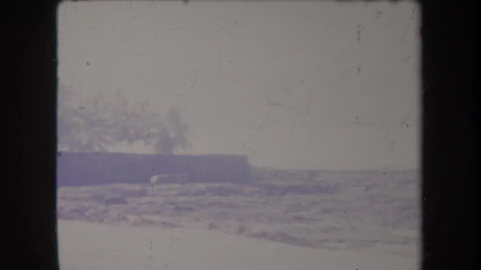 1969 Hawaii 8mm frame showing a bright beach area with low vegetation and shoreline detail, softened by age and exposure.