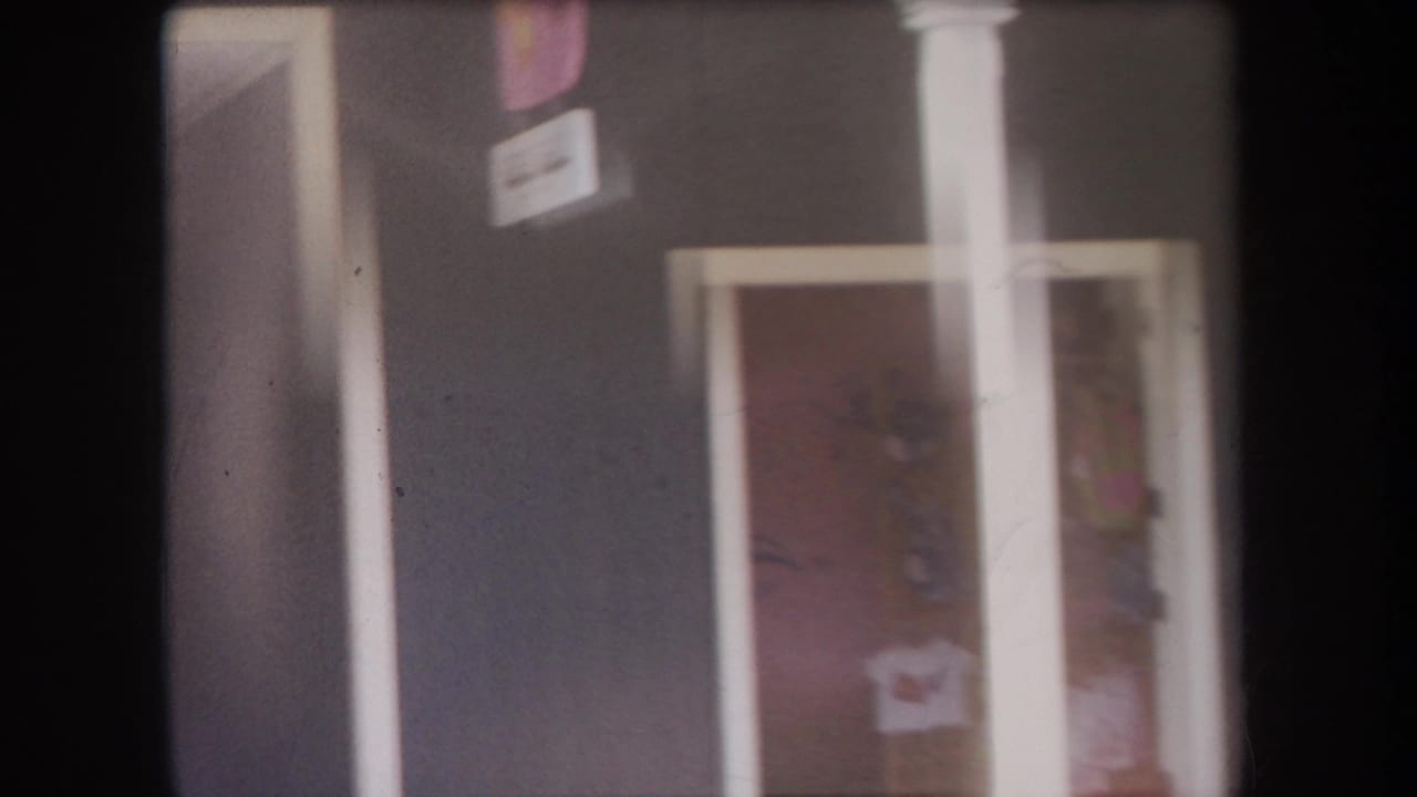 Close view of a dark exterior wall with white trim, doorway, window, and small signs near the entrance.