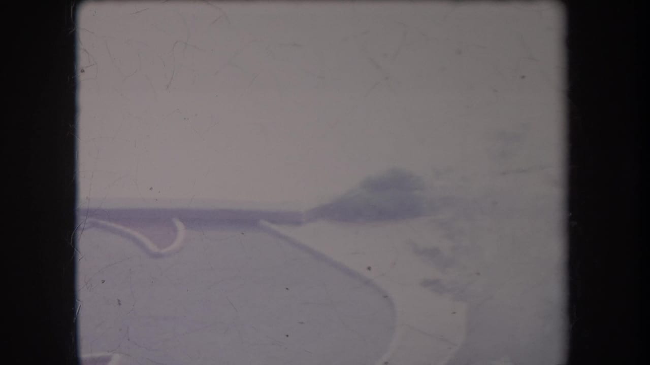 1969 Hawaii 8mm frame showing a pale curving road fork with soft greenery and distant haze.