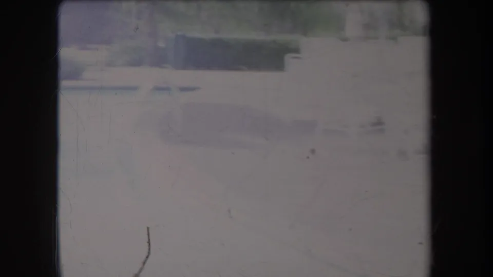 1969 Hawaii resort patio seen through faded 8mm exposure, with white furniture, closed umbrellas, hedges, and shaded architectural elements.