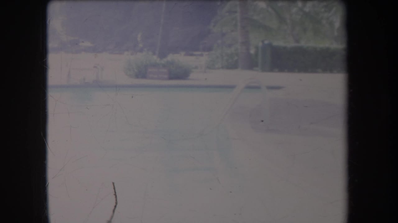 1969 Hawaii 8mm frame showing a hazy river or lagoon with faint palm and shoreline shapes in soft exposure.